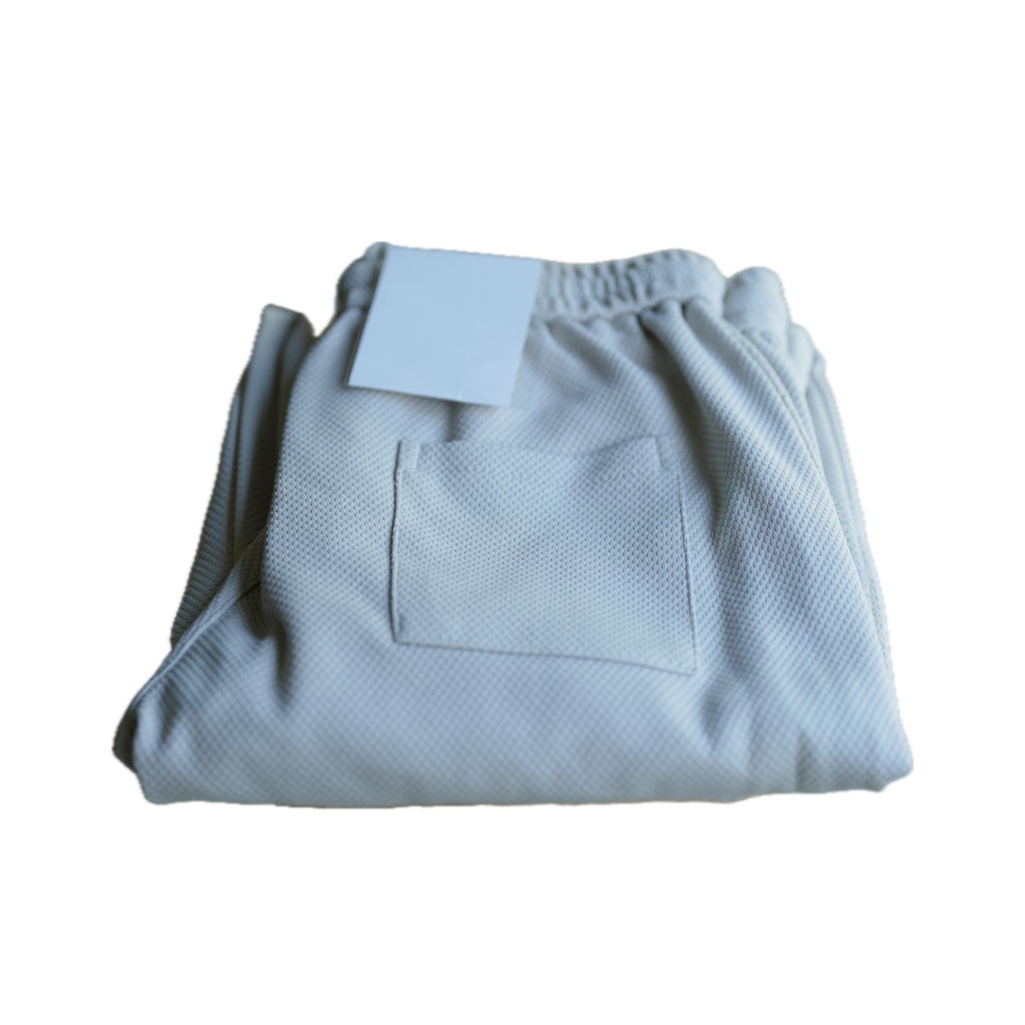 Folded light gray athletic pants with a textured fabric, featuring an attached tag and a small back pocket.