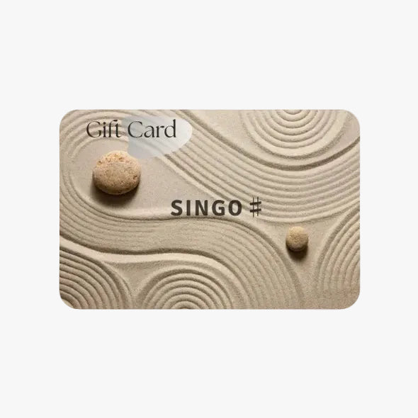 Gift card design featuring a textured sandy background with two stones and the word "SINGO" prominently displayed.