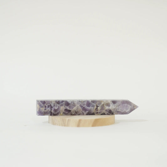 A polished Large Chevron Amethyst Tower on a small round wooden display stand, photographed against a seamless white background.