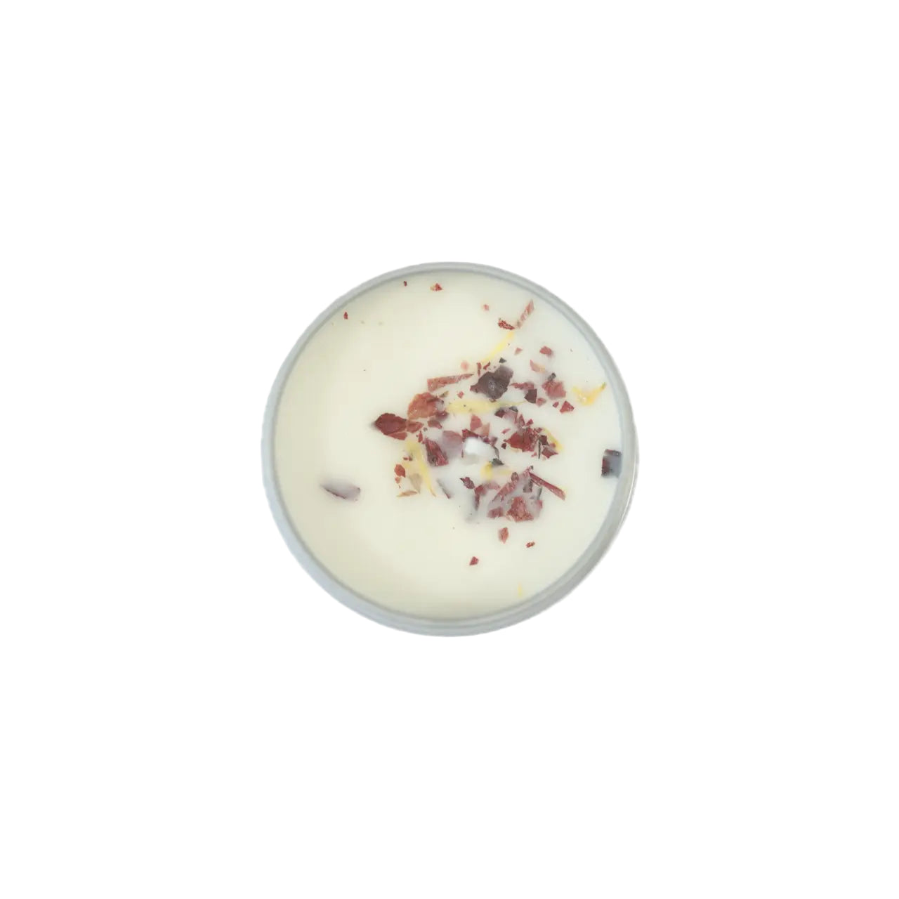 A round candle with a creamy wax surface, topped with colorful floral and herb fragments, in a simple metal container.