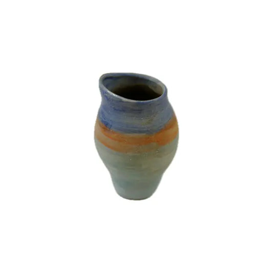 A handcrafted ceramic jug with textured stripes of blue, orange, and pale green, featuring a curved lip and a rounded body on a white background.