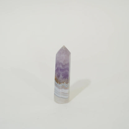 A polished natural Amethyst & Mexican Lace Agate Tower featuring lavender purple, white, and light brown agate banding, standing upright on a plain white background.
