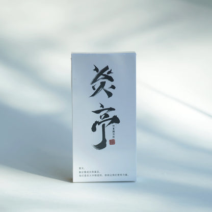 A tall, narrow white product box with large black Chinese calligraphy and small red seal details, photographed upright on a light surface with soft shadows.