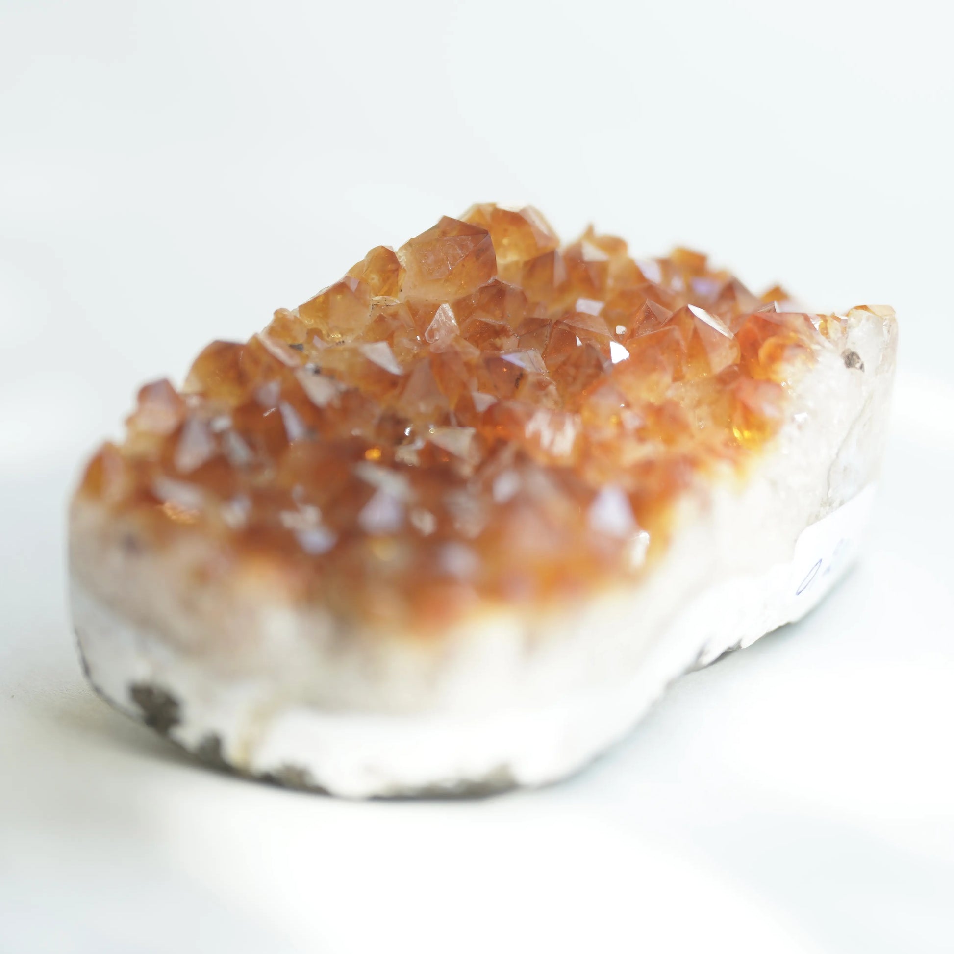A natural crystal cluster specimen with translucent amber-brown crystals on a white matrix, photographed on a clean white background.