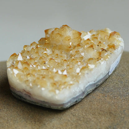 A natural crystal cluster specimen with clear and golden-yellow points on a white to gray base, photographed close-up against a neutral gray background.