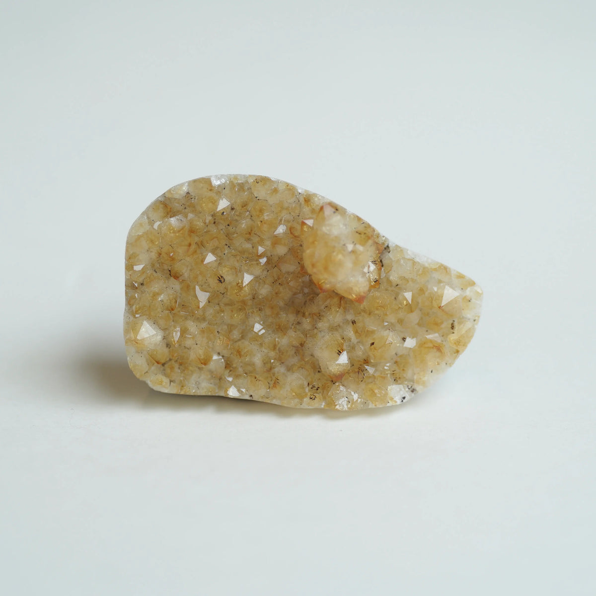 A raw crystal cluster specimen with natural triangular crystal points, showing a mix of beige, light brown, and translucent white quartz-like structures, photographed on a clean white background.