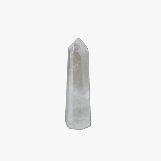 A natural clear quartz crystal point tower standing upright on a neutral gray surface with a soft shadow cast to the right.