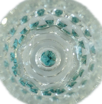 Close-up view of a crystal cup filled with turquoise stones, showcasing intricate layering and light refraction.