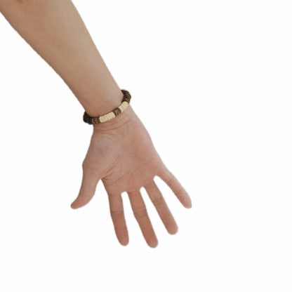 Hand wearing a coffee bean bracelet on a white background