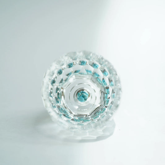 Close-up of a Crystal Turquoise Faceted Cup with turquoise reflections on a pale background.