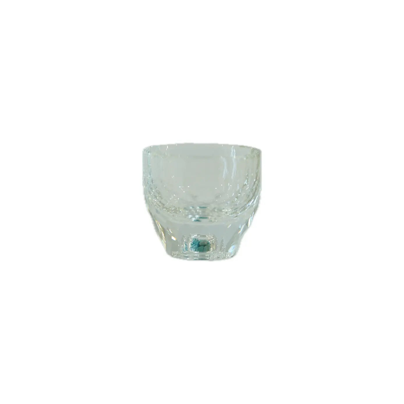 Clear glass tumbler with a curved design and decorative patterns around the rim, resting on a plain background.