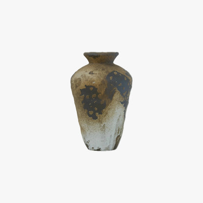A rustic ceramic vase with a tapered shape, featuring a mottled glaze of brown, beige, and dark charcoal gray with organic splatter patterns.