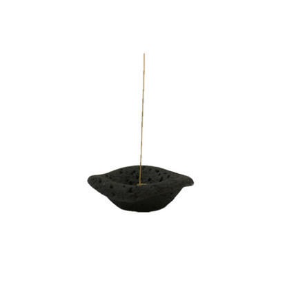 A black, cement incense holder with a dish shape on a white background.