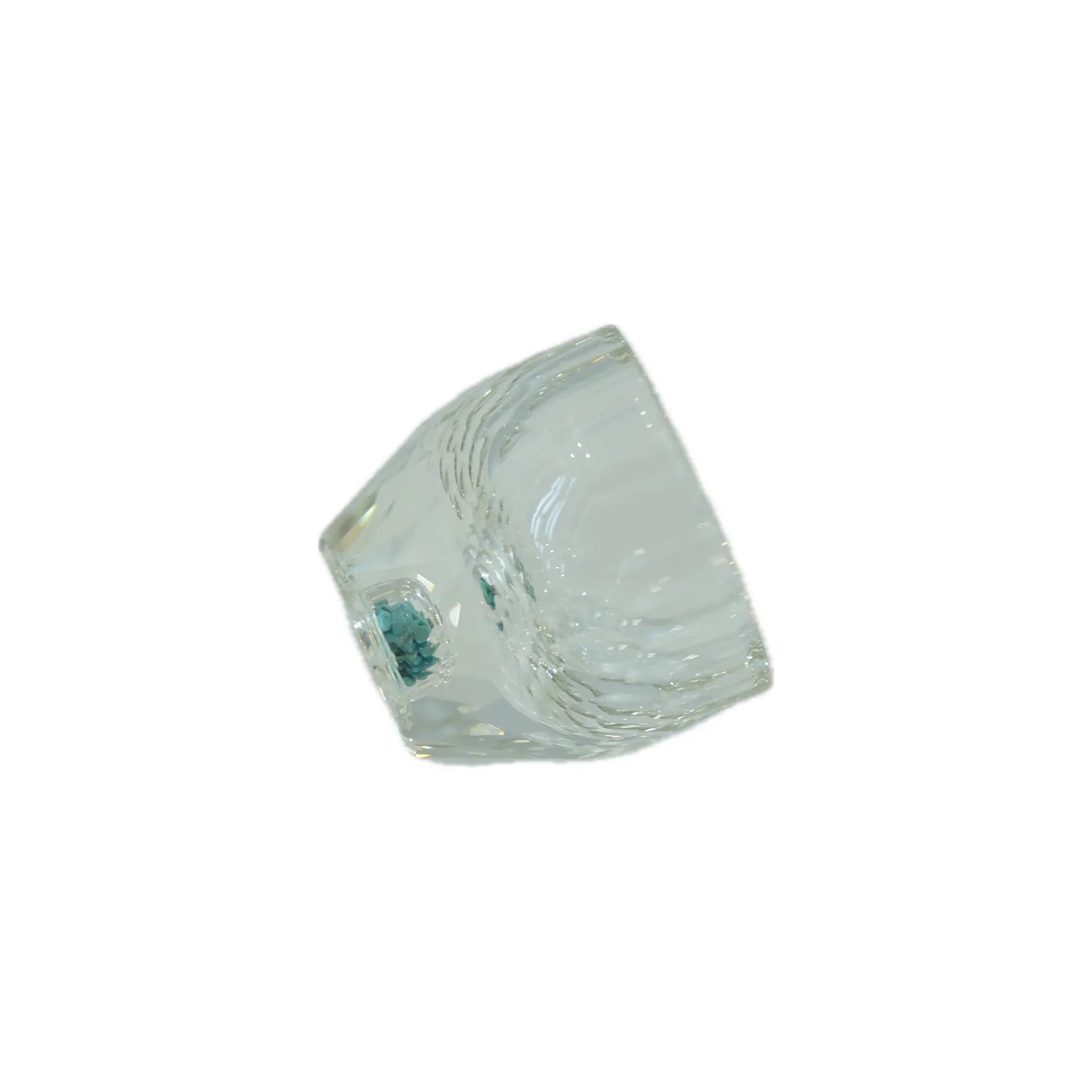 A clear glass cup positioned sideways, featuring a textured surface and a small blue accent at the base.