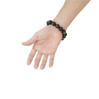 Hand-wear shot of the Silver Sheen Obsidian bracelet, showcasing the unique chatoyancy and smooth, weighted feel of the 18mm beads, ideal for mindfulness and protection at Singoau.