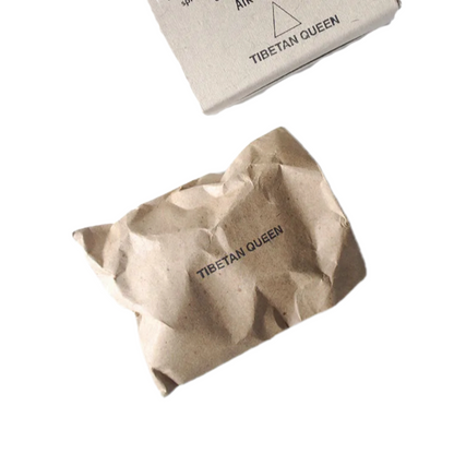 Crumpled brown paper package labeled "TIBETAN QUEEN," partially overlapping a flat box with the same label in a minimalist style. Good for meditation, relaxation, grounding, and spiritual clarity