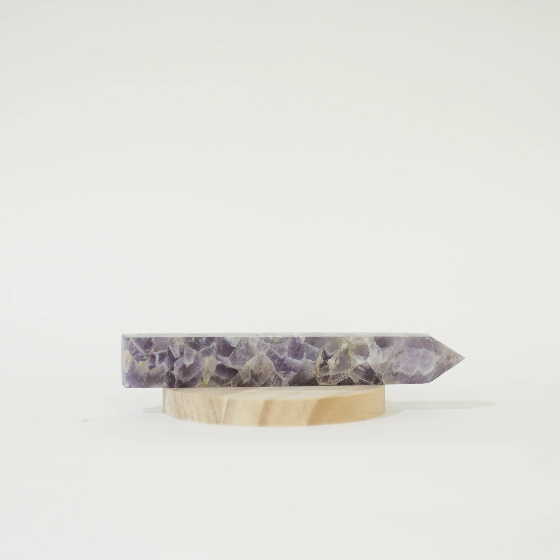 A polished Large Chevron Amethyst Tower on a small round wooden display stand, photographed against a seamless white background.