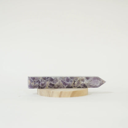 A polished Large Chevron Amethyst Tower on a small round wooden display stand, photographed against a seamless white background.