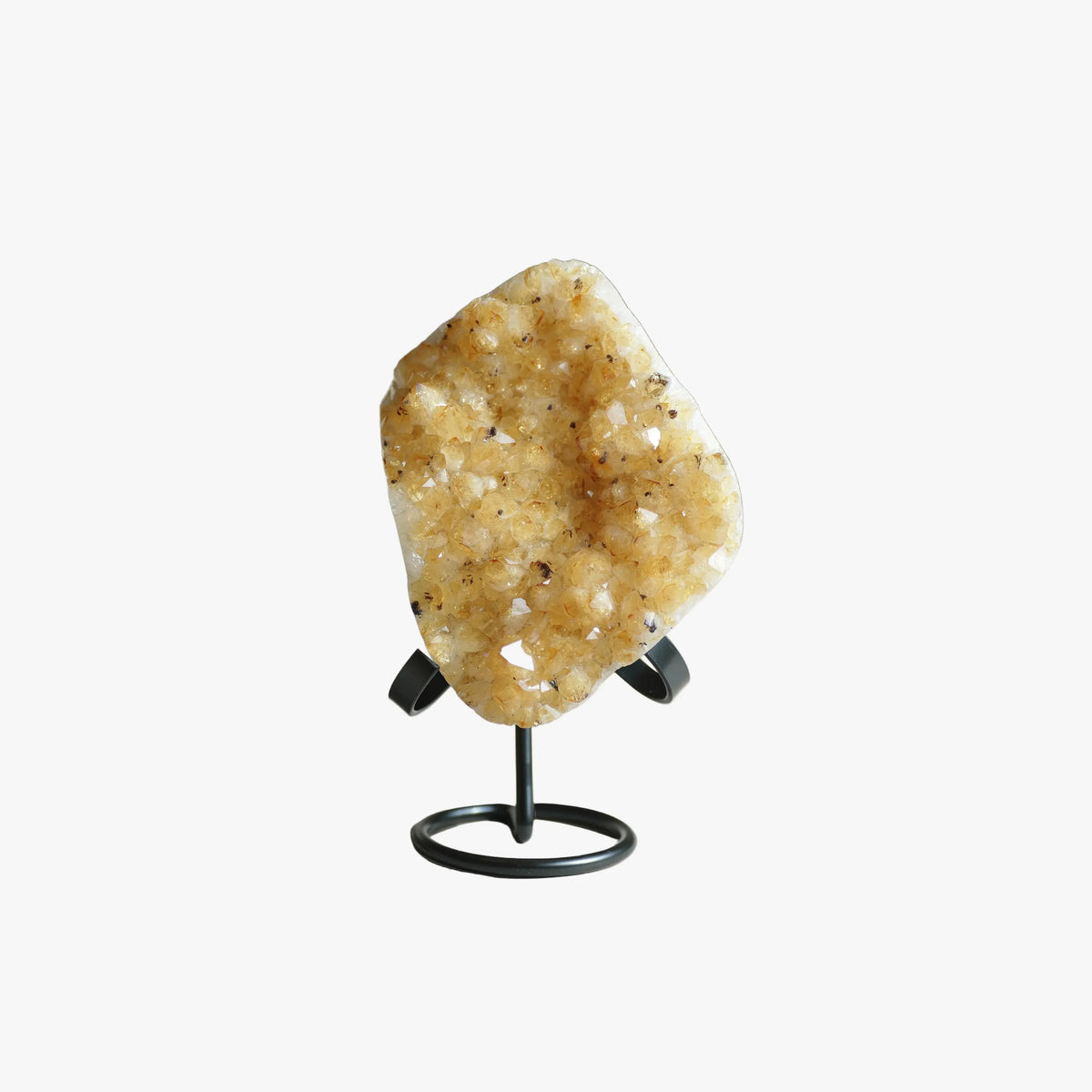 A natural crystal cluster geode specimen with a rough, porous golden-yellow interior, displayed on a black metal stand against a plain white background.
