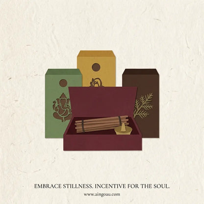 A stylized product illustration showing a set of incense-related items: three tall boxes in green, mustard yellow, and dark brown, with an open dark red box in front containing incense sticks and a small brass incense holder. Text below reads 'EMBRACE STILLNESS.
