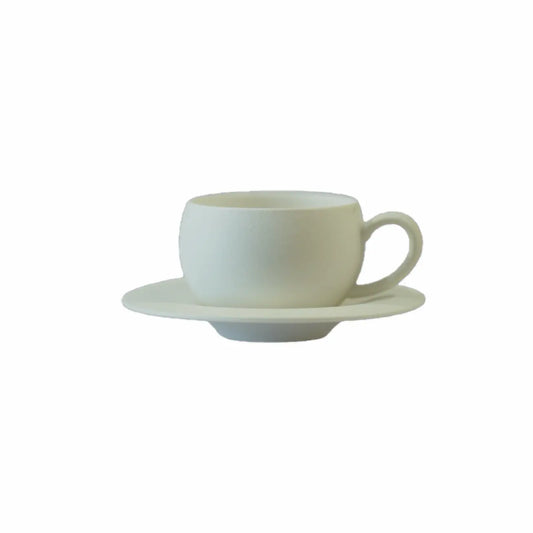 White ceramic cup with a textured finish, resting on a matching saucer, isolated on a white background.