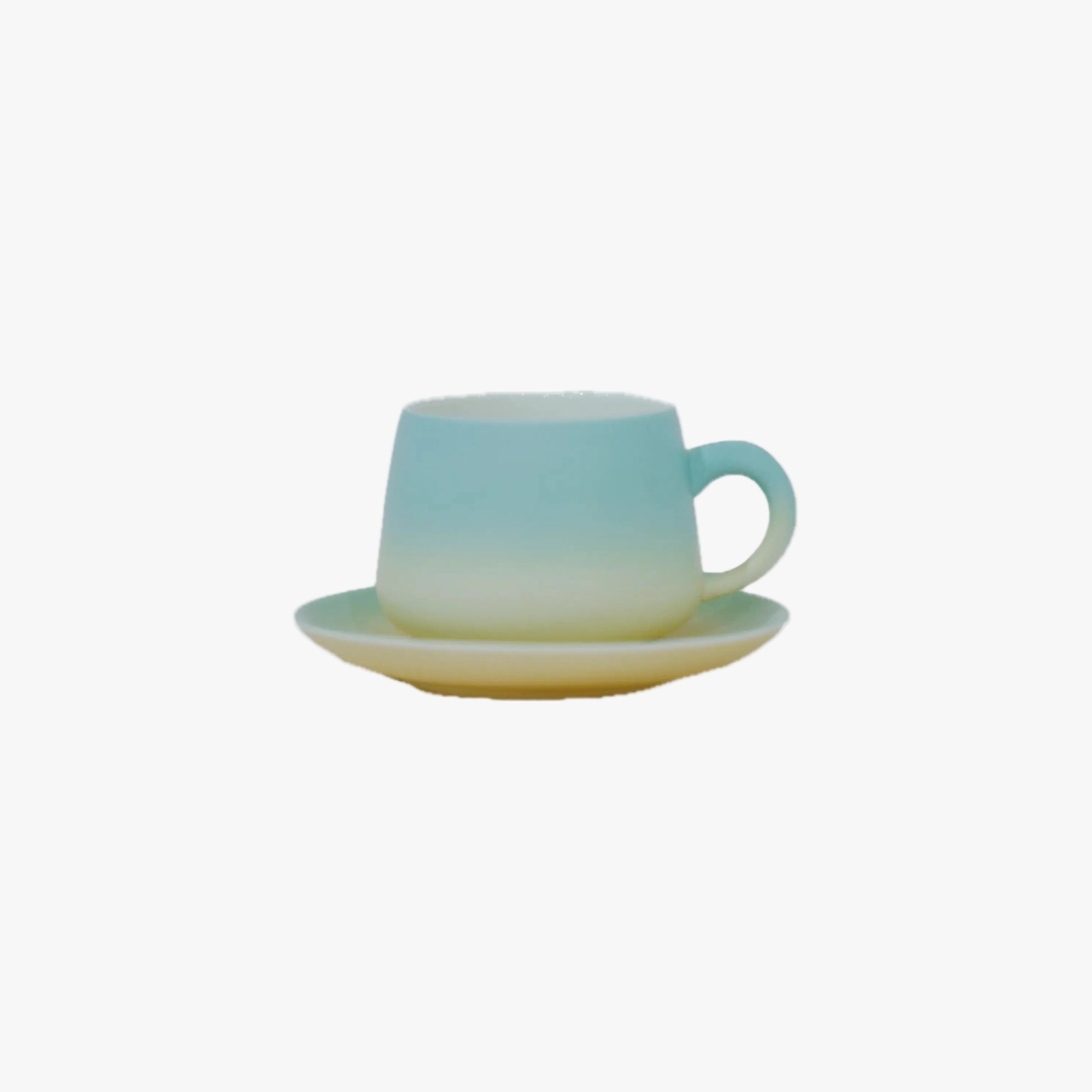 A small ceramic cup with a matching saucer, featuring a smooth gradient design that transitions from light blue at the top to pale yellow at the bottom, set against a plain white background.