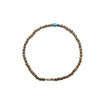 Close-up of a beaded bracelet featuring brown patterned beads, with central gold accent and a vibrant blue decorative bead.