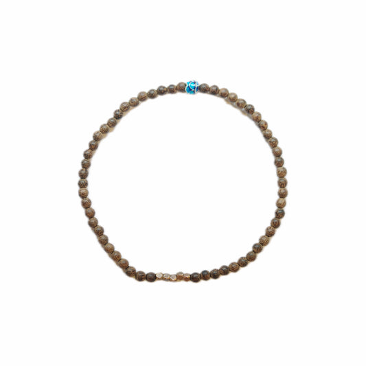Close-up of a beaded bracelet featuring brown patterned beads, with central gold accent and a vibrant blue decorative bead.