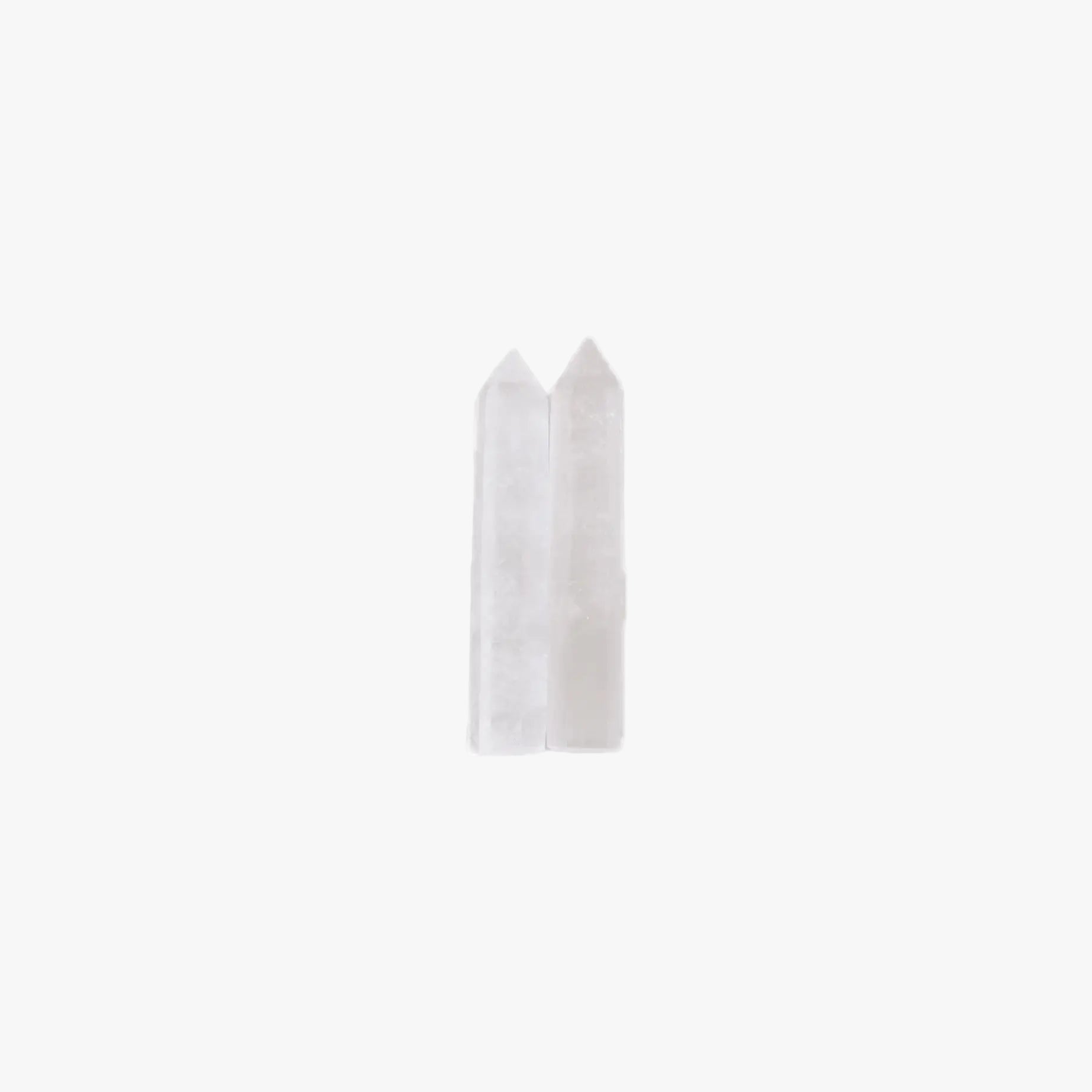 Two small translucent white pointed crystal-like pieces standing upright against a plain white background.