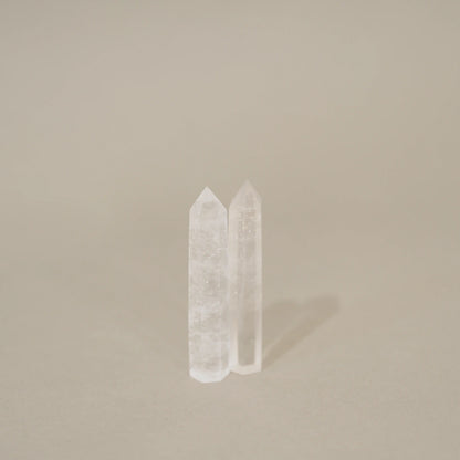 Two clear crystal point towers standing upright on a neutral beige background.