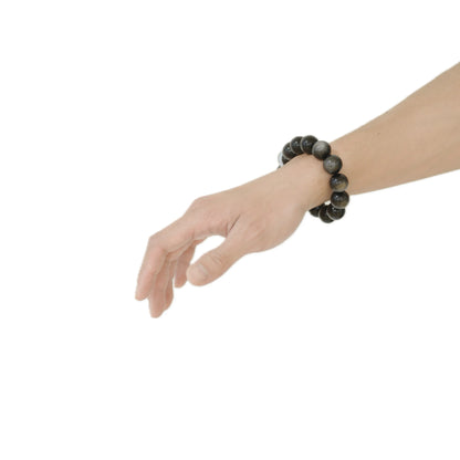 Angled view of the Silver Sheen Obsidian bracelet on a wrist, capturing the captivating natural light play or ‘sheen’ that symbolizes intuition and inner wisdom, handcrafted by Singoau.