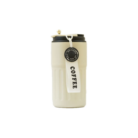 A stylish, white reusable coffee cup with a black lid and a tag that reads "COFFEE," featuring a decorative gold knob.