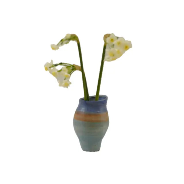 A small, blue and terracotta pottery vase holds delicate white flowers with yellow centers on a white background, adding charm to a simple decor.