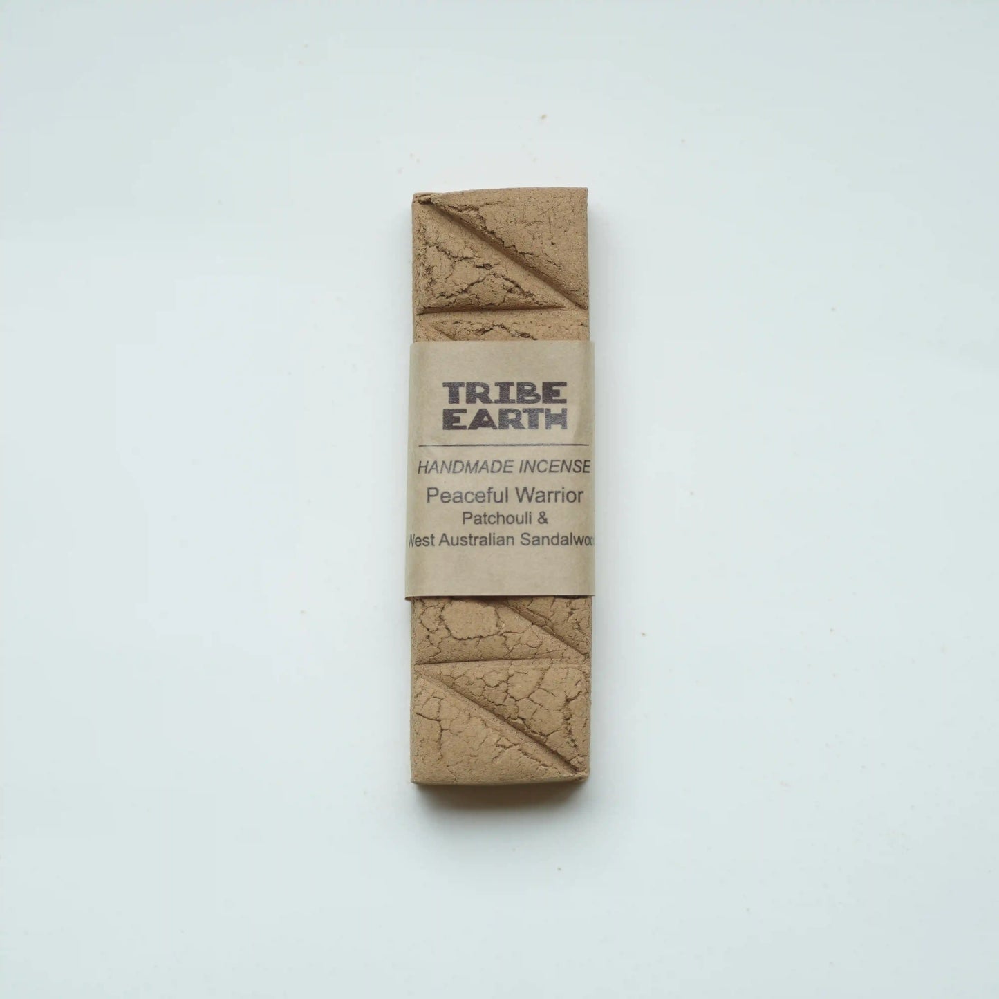 A single rectangular bar of Tribe Earth Handmade Incense, 'Peaceful Warrior' patchouli and Australian sandalwood, wrapped in a kraft paper band, photographed on a clean white background.