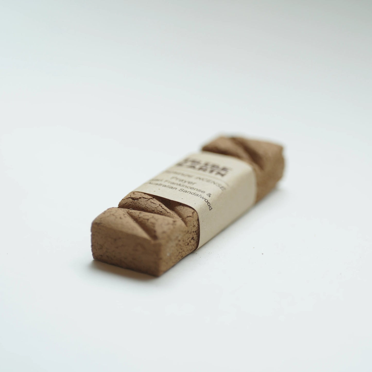 A single Tribe earth prayer incense in a plain kraft paper band, photographed on a clean white background.