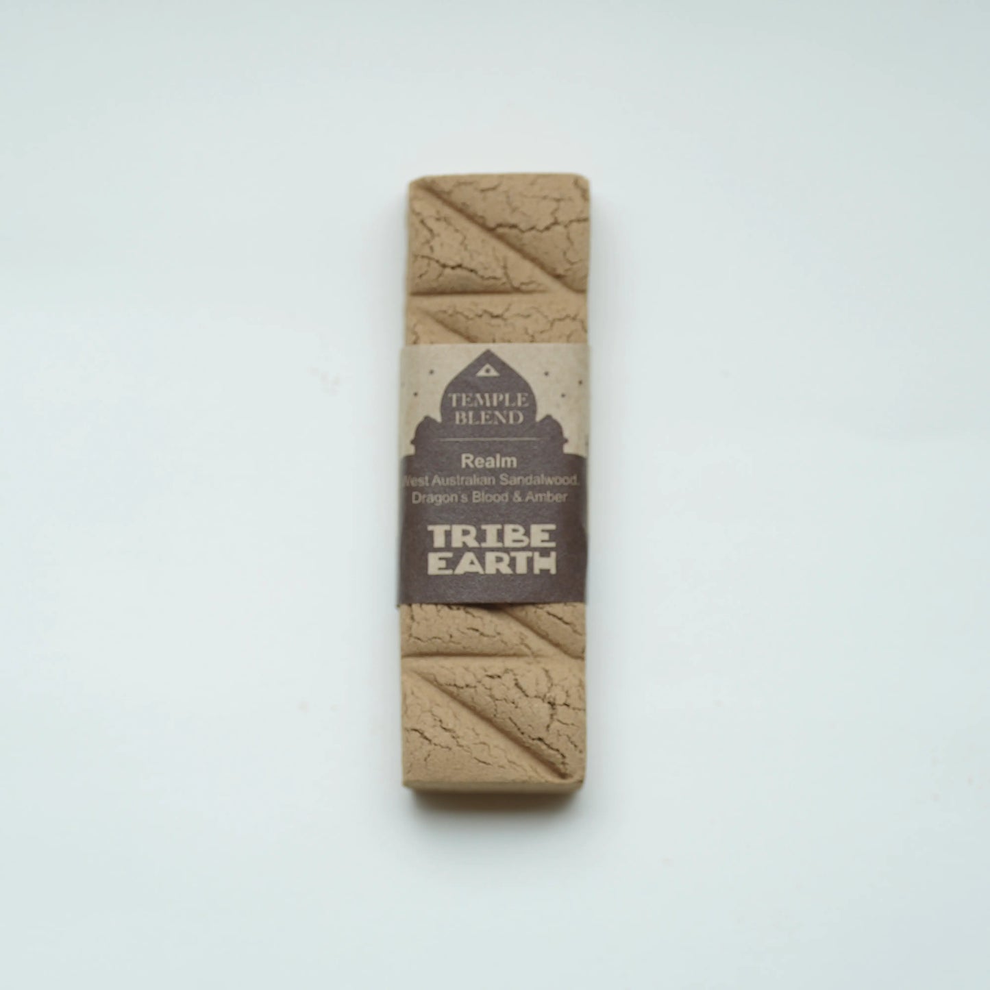 A rectangular Temple Blend Tribe Earth dog toy made of natural earth-toned material, wrapped in a brown paper band label, centered on a plain white background.