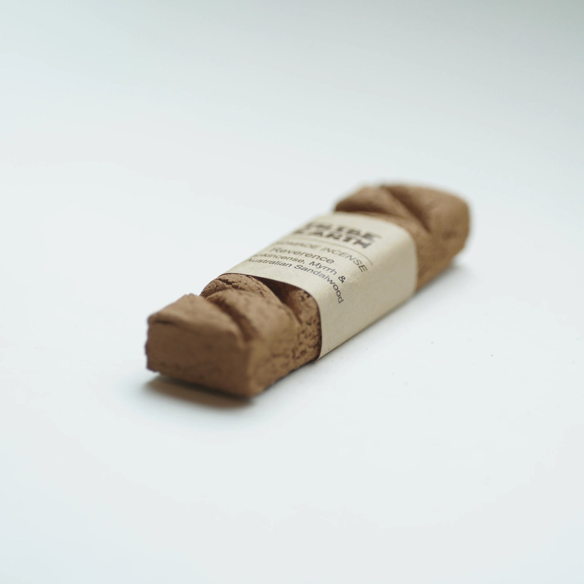 Tribe earth reverence incense wrapped with a beige paper band label, photographed on a clean white background.