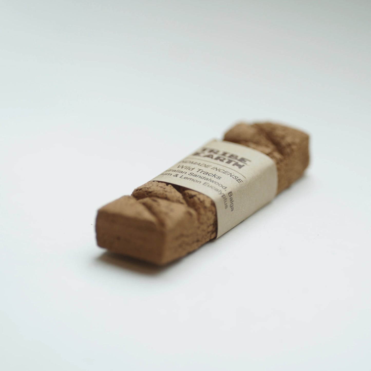 A natural cork roller with a kraft paper label reading 'TRIBE EARTH', photographed on a clean white background.