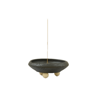 A minimalist, Wabi-Sabi Style ceramic incense holder on three wooden legs, featuring a slender stick protruding from the center.  It symbolizes balance and grounding energy.