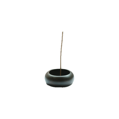 Black wood incense burner with a single incense stick on a white background