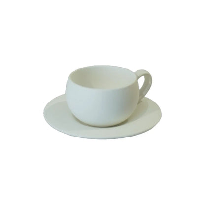 A simple, elegant white coffee cup with a handle sits on a matching saucer against a plain background.