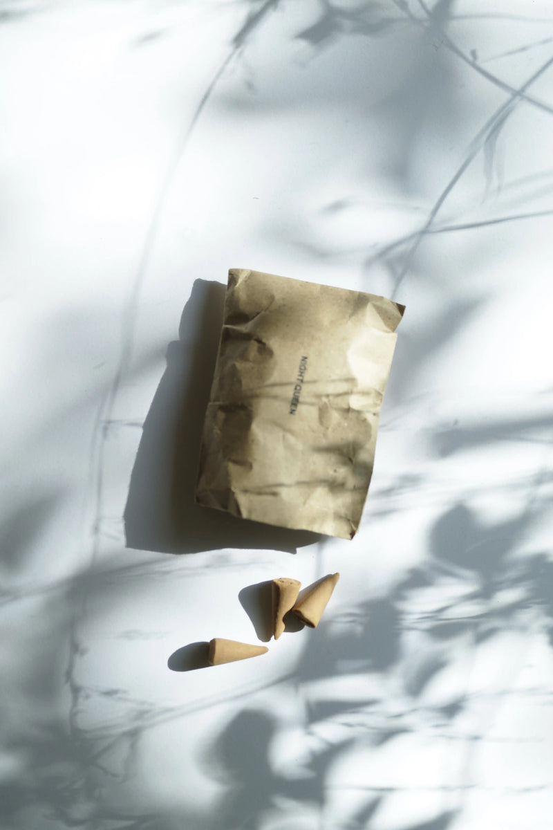 Minimalist flat lay of handmade incense cones and recycled paper packaging in soft natural light