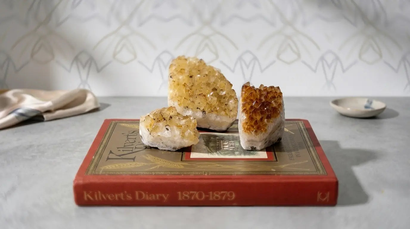 Three citrine crystal clusters displayed on the cover of "Kilvert's Diary 1870-1879" book on a gray surface.
